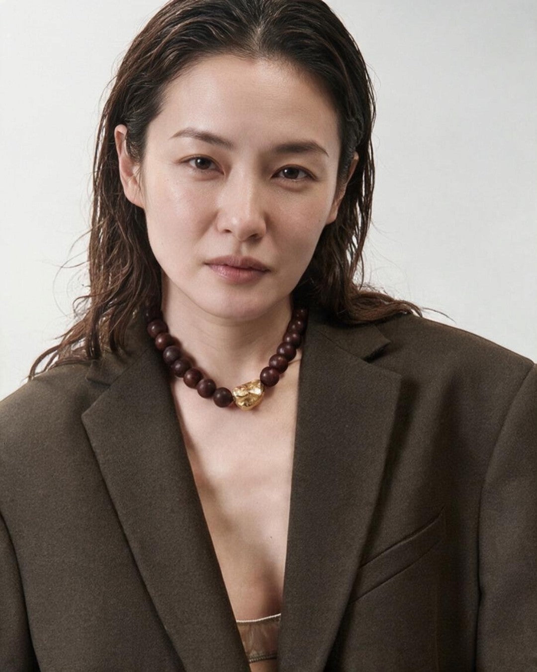 ALYSI（アリジ）ウッドビーズ チョーカーネックレス、ブラウンのジャケットに合わせたモデル着用の上半身アップ